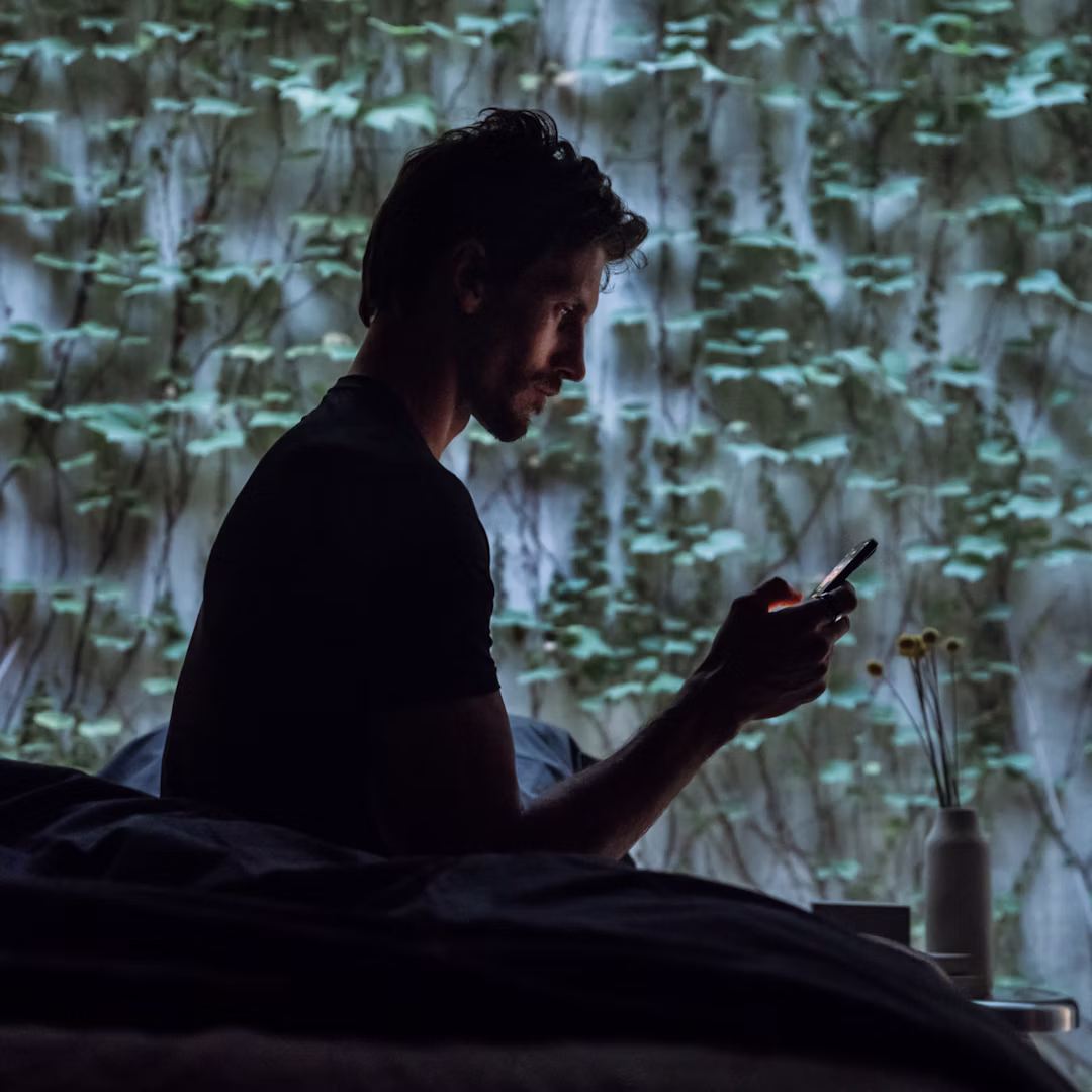 Homme qui démarre sa journée en consultant l'application Oura