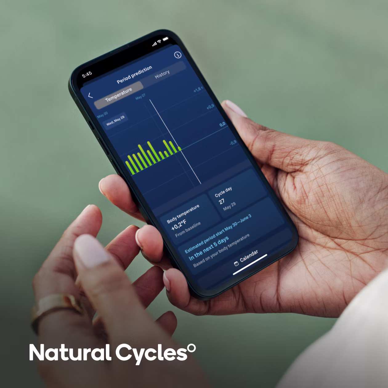 Personne tenant un smartphone dans la main droite avec l'application Natural Cycles ouverte et la KEORA Ring à l'index droit