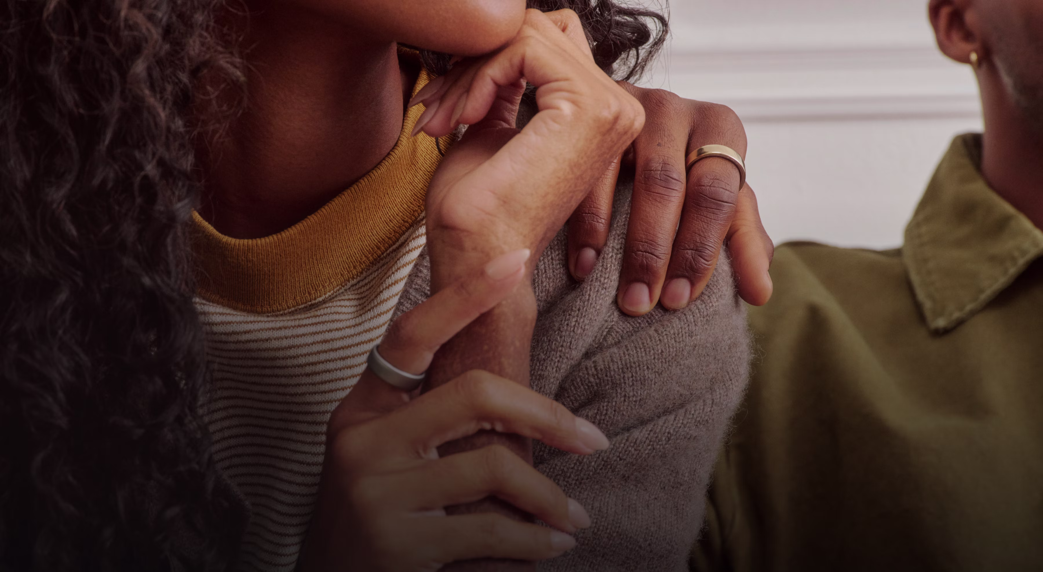 Une personne pose sa main sur l’épaule d’une autre personne, toutes deux l’Oura Ring 5 au doigt