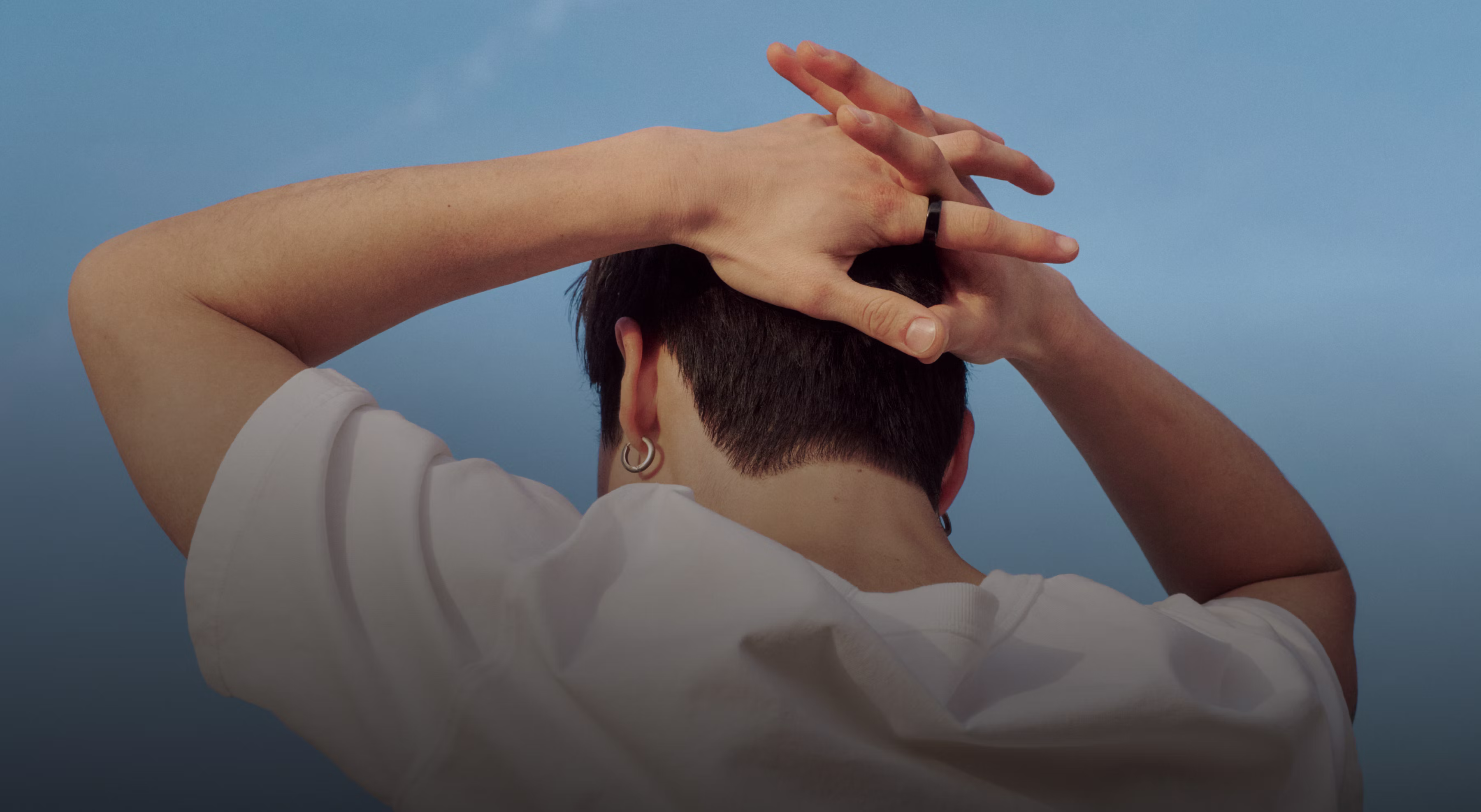 Une personne a les mains jointes derrière la tête, l’Oura Ring 5 au doigt